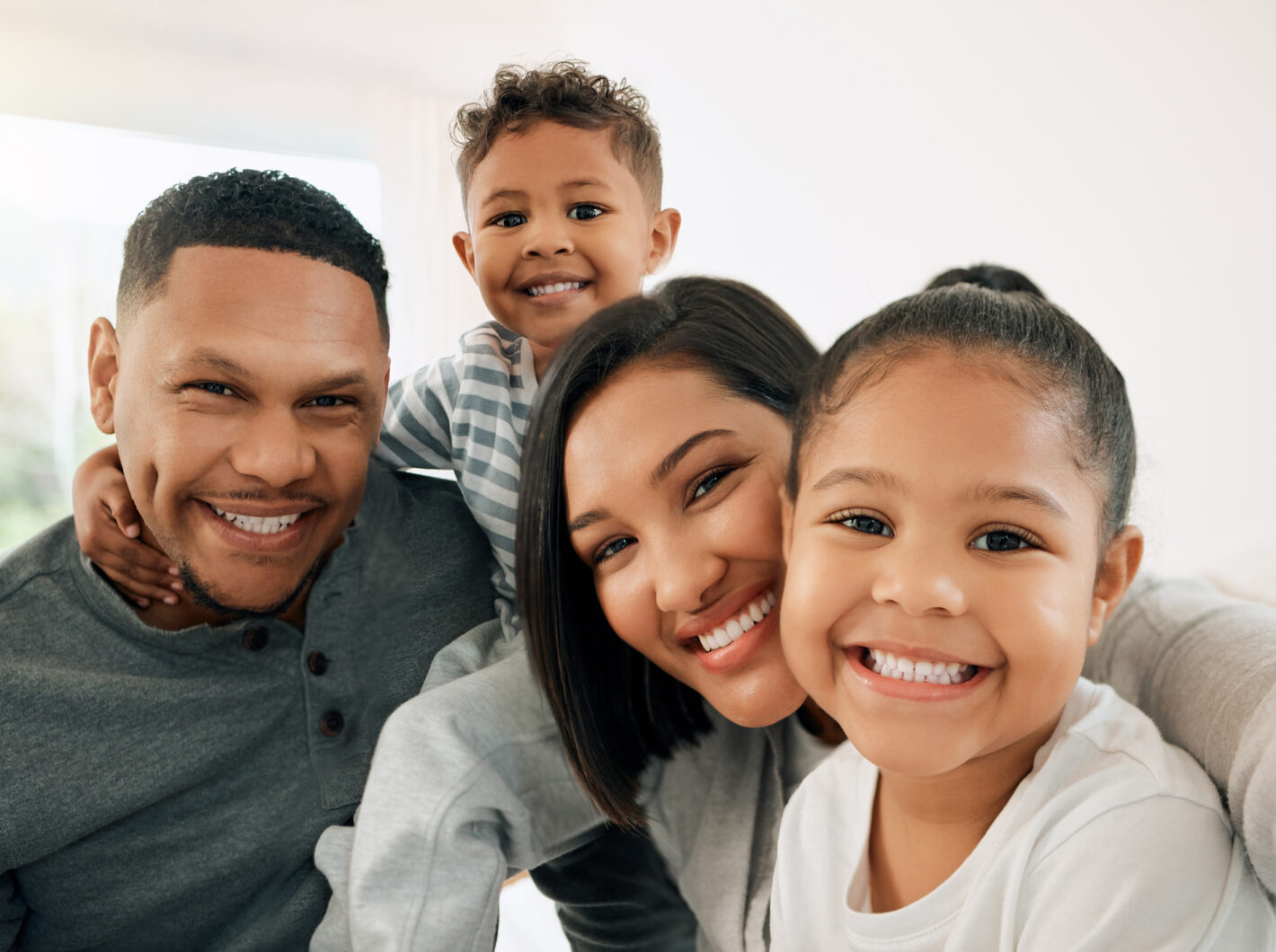 Family of four smiling together indoors
