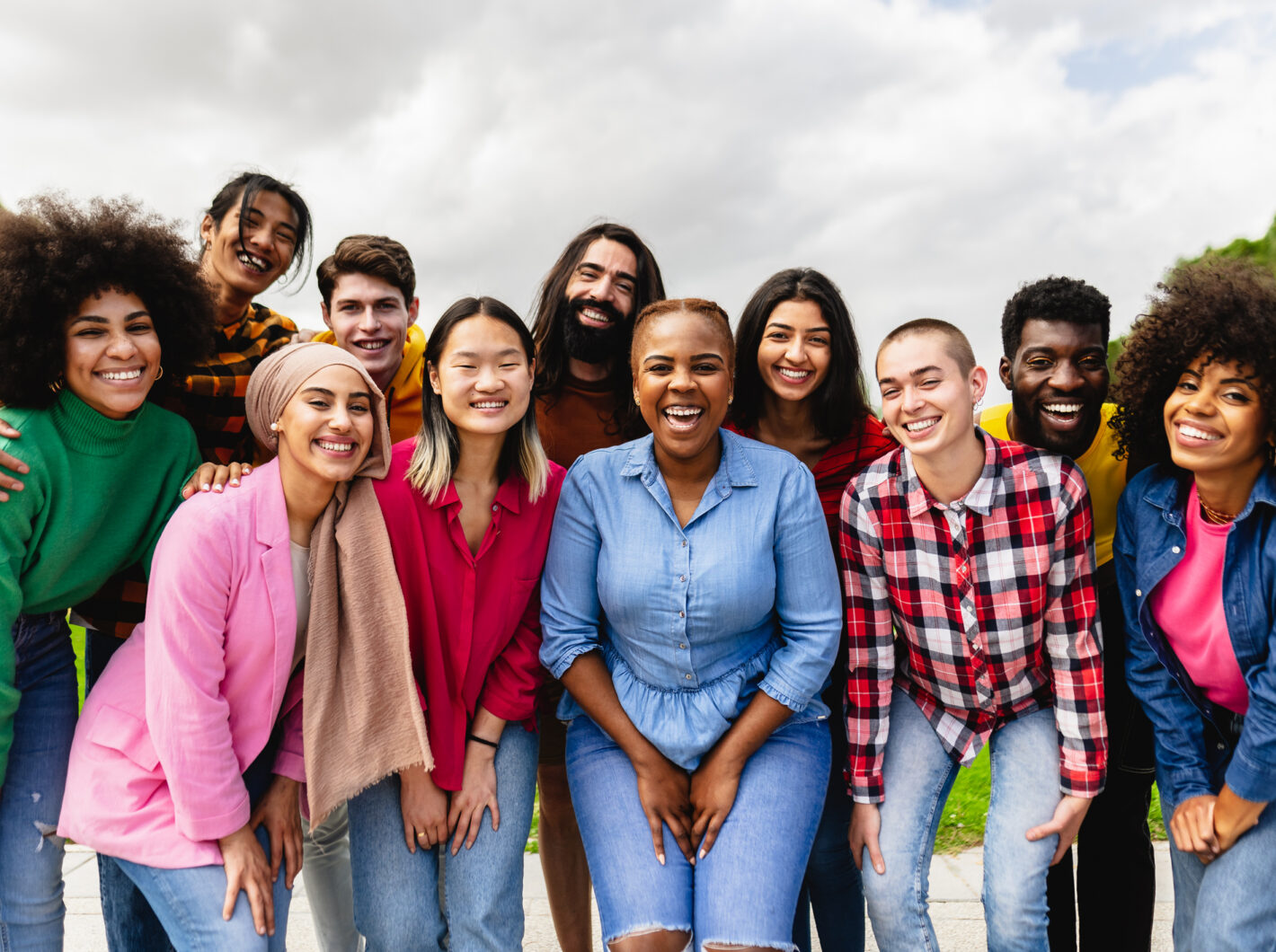 Diverse group of smiling people outdoors, showing happiness and togetherness.