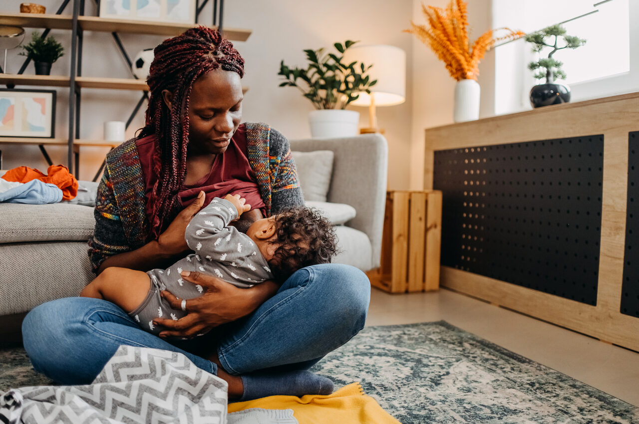 Photo of a woman breastfeeding a child in a cozy living room setting.