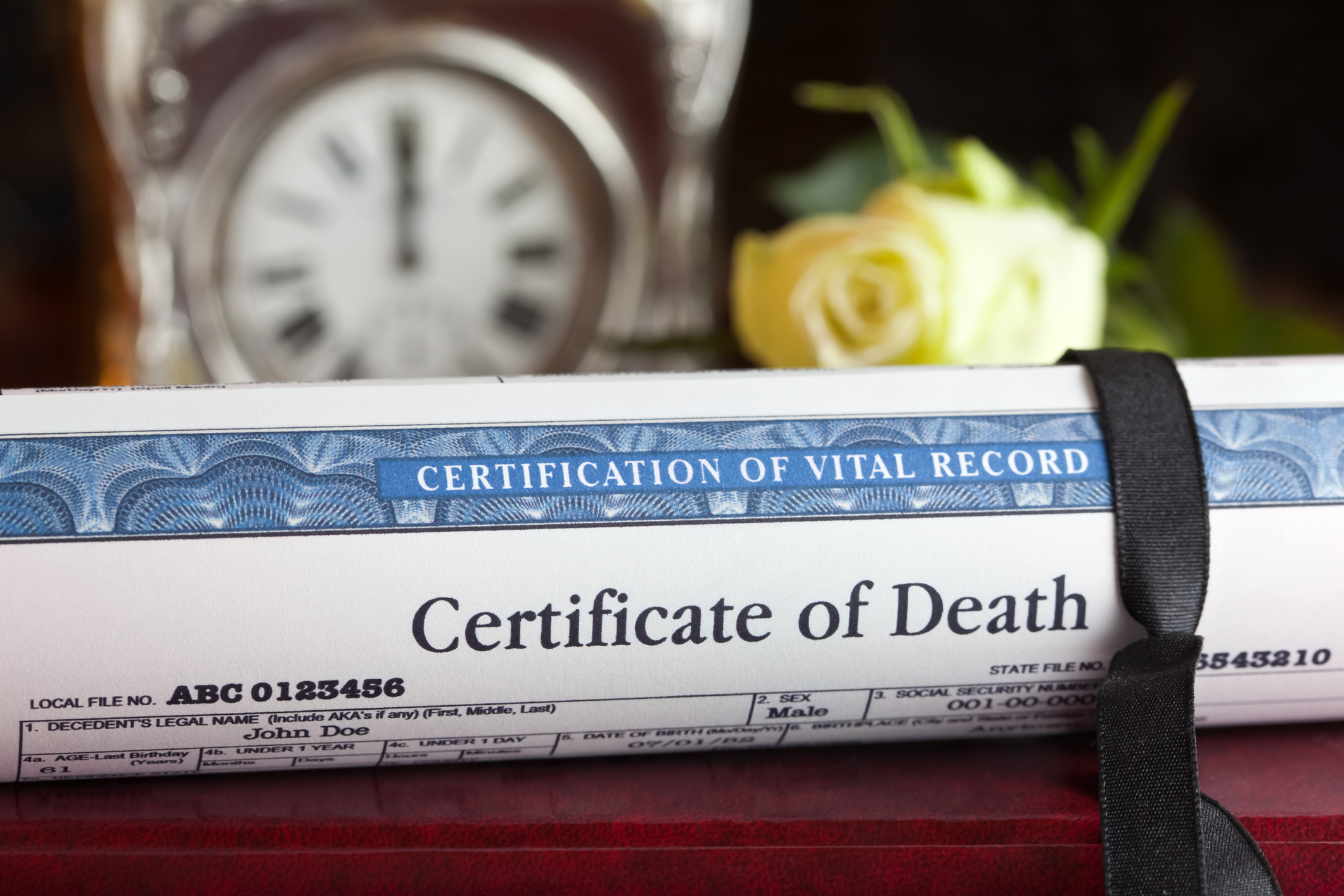 Photo of a rolled up death certificate with a black ribbon