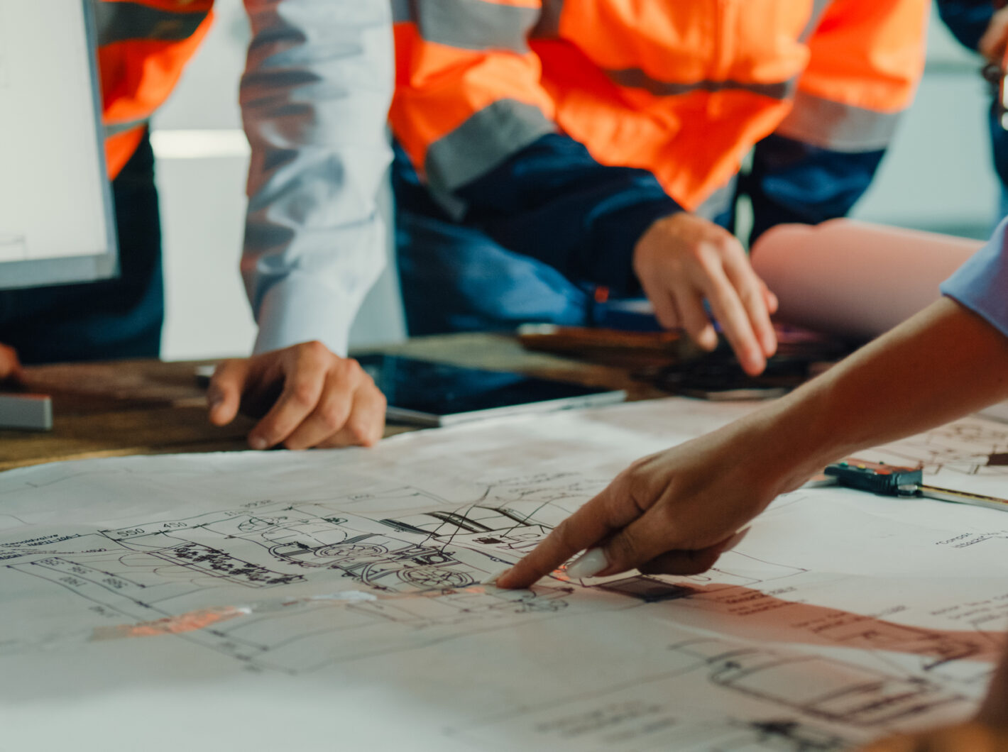 Photo of people pointing at construction blueprints