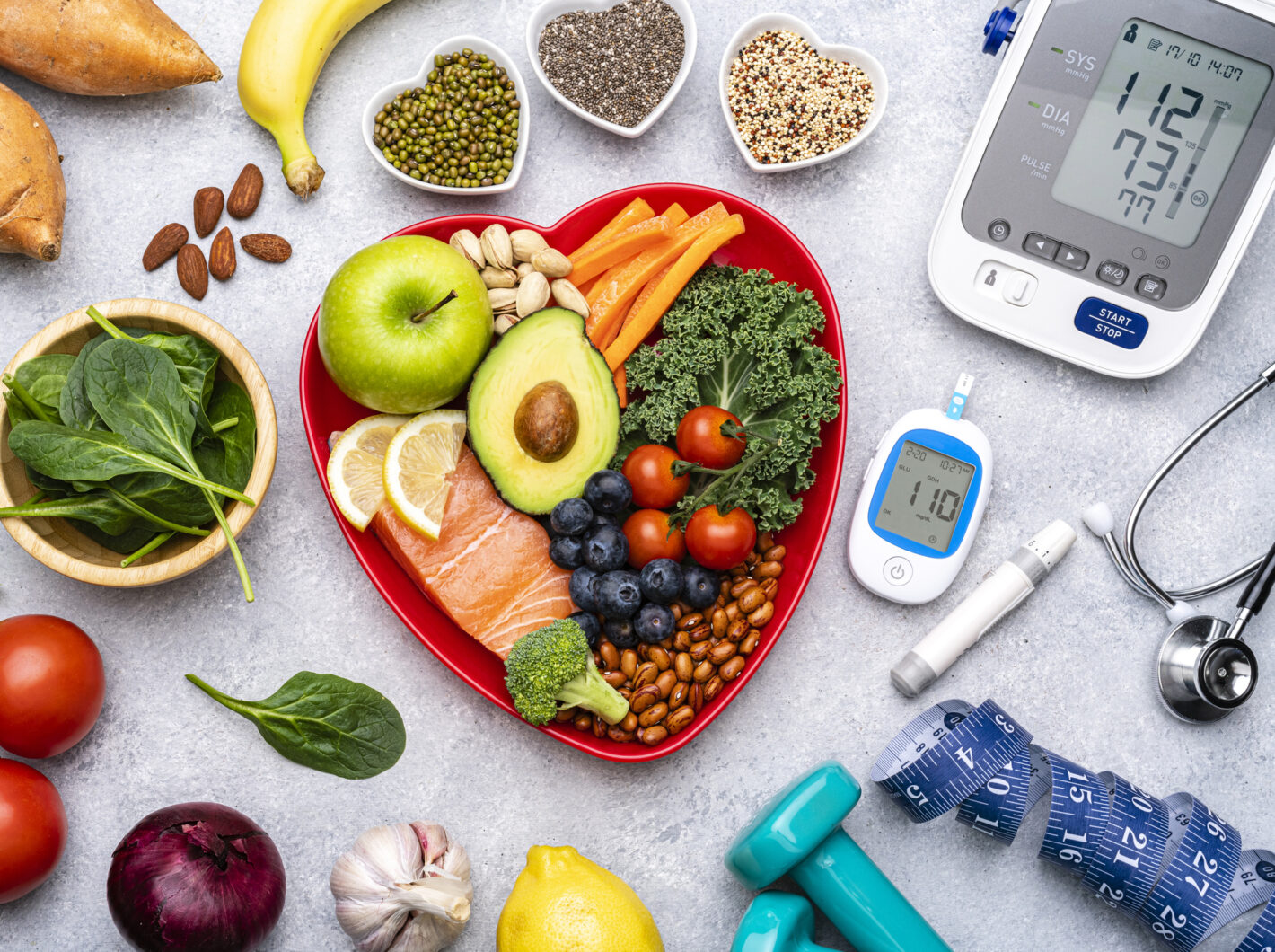 Photo of healthy foods in a heart-shaped bowl sitting next to a blood sugar monitor