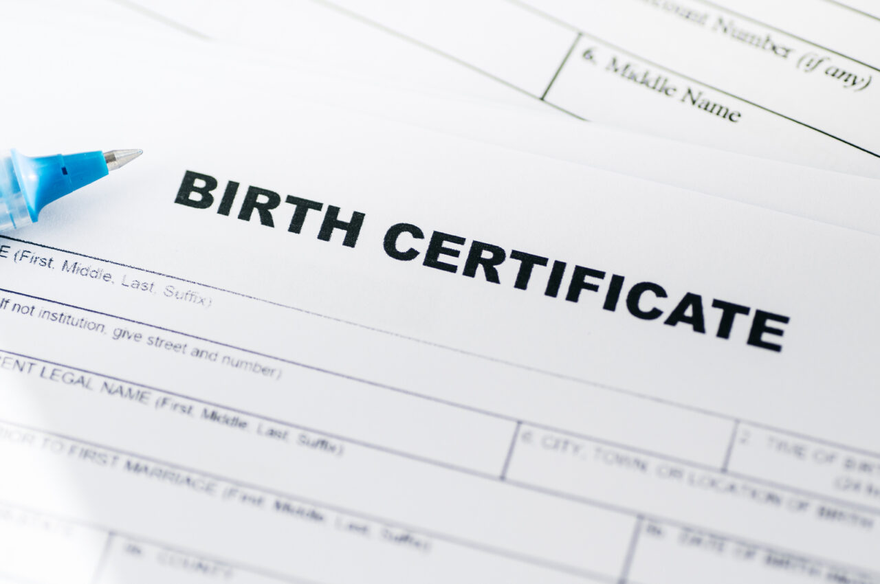 Birth certificate document with blue pen on top.